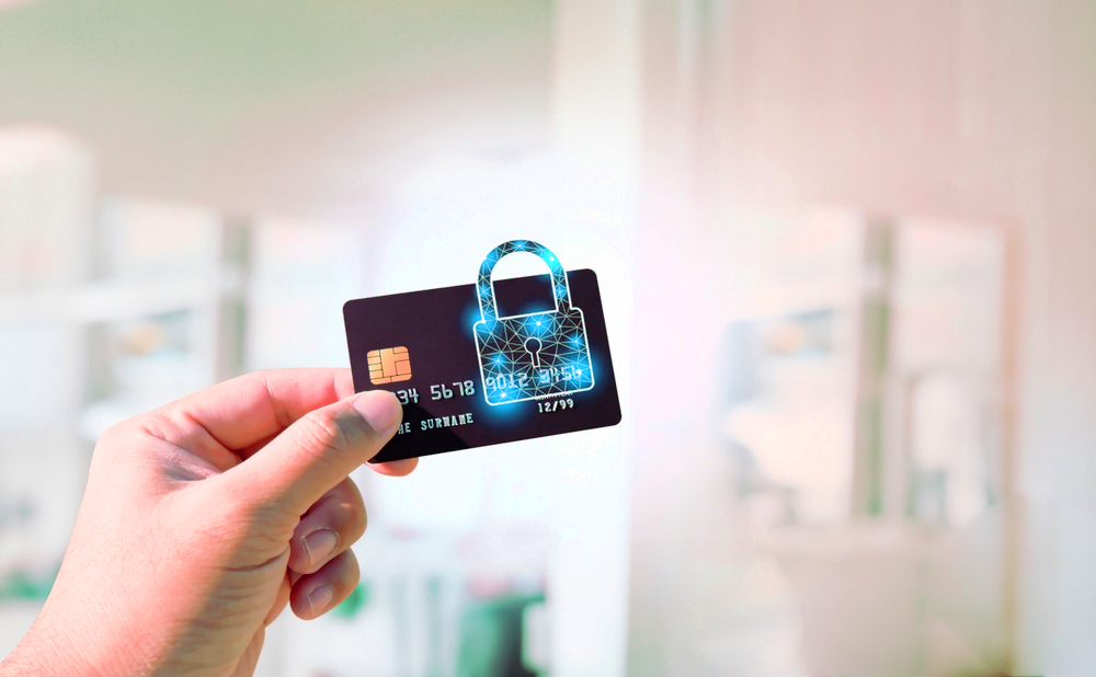 Kobieta trzymająca w ręce kartę płatniczą z symbolem kłódki.